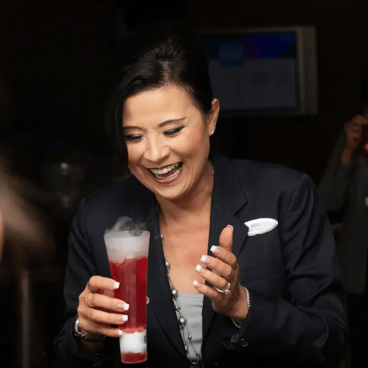 Woman in formal attire smiling while holding smoking mocktail drinks