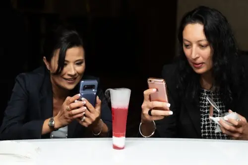 Woman in formal attire smiling while holding smoking mocktail drinks
