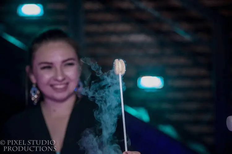 Woman in formal attire smiling while holding smoking mocktail drinks